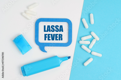 On a white and blue table are pills, a marker and a blue plaque with the inscription - Lassa fever
