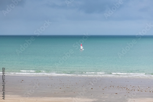 Beautiful beach at Agon-Coutainville in Normandy, with a sailing boat on the sea 