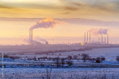 Chimneys and cooling towers at sunset. A combined heat and power plant and gas processing plant on the horizon. The picture was taken in Russia, near the city of Orenburg
