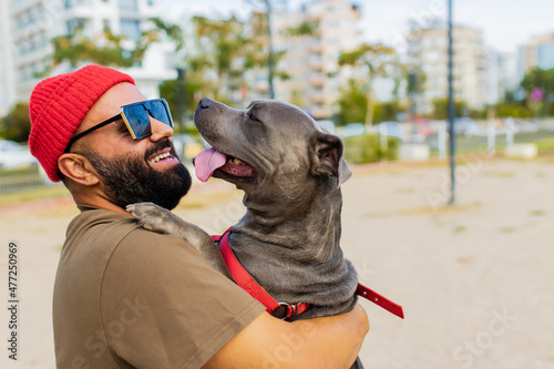 Photography portrait of happy man in red hat and sunglasses with american terrier in dogs wa