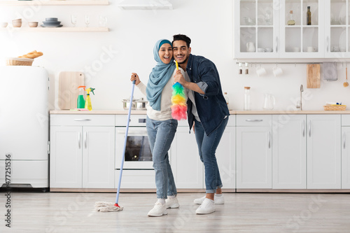 Loving muslim couple cleaning floor and having fun in kitchen © Prostock-studio