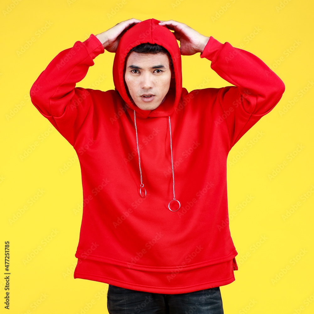 Young arrogant Asian boy in red sweatshirt with hood confidently standing with face up and reaching hand out to convince man to proudly fight against cold winter Young arrogant Asian boy in red sweatshirt with hood confidently standing with face up and reaching hand out to convince man to proudly fight against cold winter