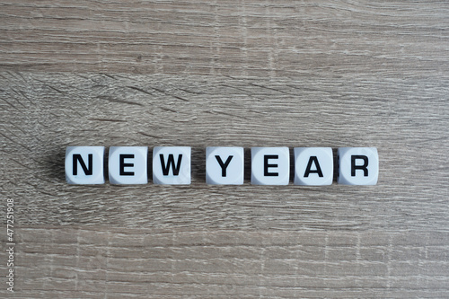 New Year wording on a white cube and wooden table as background