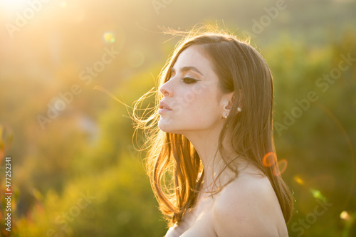 Young woman outdoor enjoying the sunlight. Spring romantic casual woman portrait. Beautiful girl looking eways in summer park outdoor, close up beauty young female face. photo