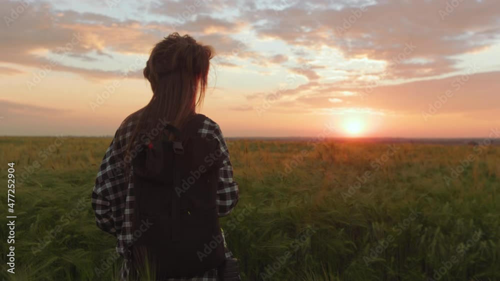Woman with backpack enjoying sunset among summer field Woman with backpack enjoying sunset among summer field