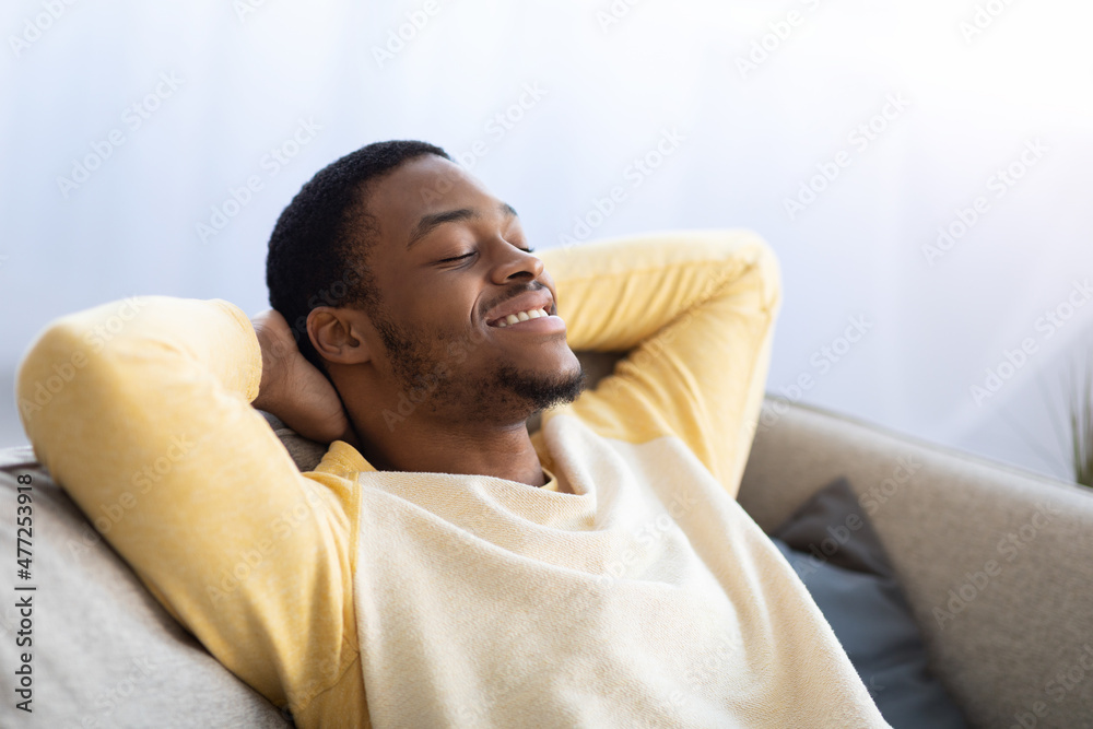 Closeup of black guy reclining on couch with closed eyes Closeup of black guy reclining on couch with closed eyes