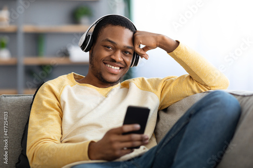 Cheerful black guy watching movie on mobile phone