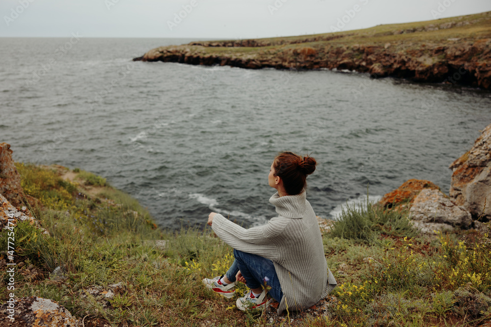 portrait of a woman in a gray sweater stands on a rocky shore nature unaltered