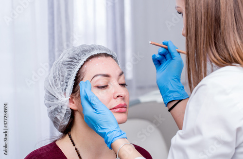 Injection facial rejuvenation. The cosmetologist injects cosmetic injections into the muscles of the forehead to smooth wrinkles. Beautiful woman at the reception of a beautician.