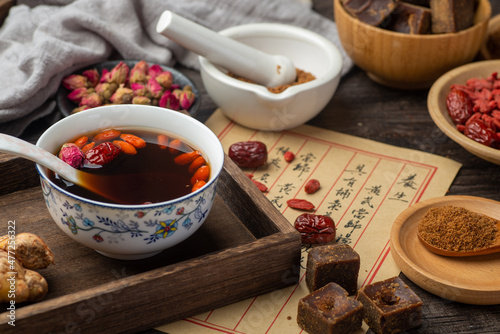 Fototapeta Naklejka Na Ścianę i Meble -  Brown sugar ginger jujube tea and Chinese classical medical books on the table