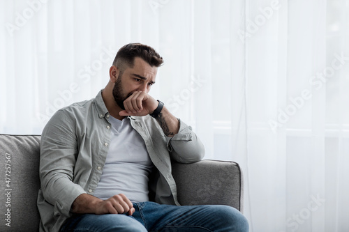 Depressed sad attractive man crying on sofa at home, feeling lonely, tired and worried © Prostock-studio