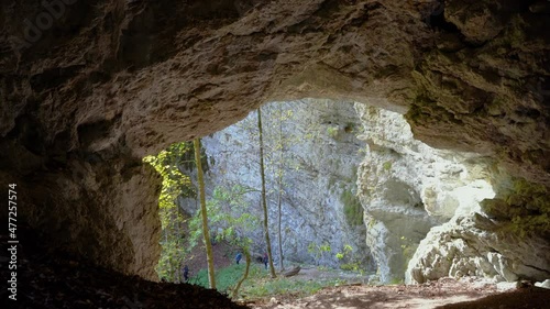 Cinematic shot inside karst cave. Limestone rock formations in Pokljuka Gorge, Slovenia. Amazing and pristine nature. Glacial valley. Colorful autumn season. People descending on a steep slope. Tilt photo