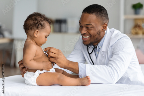 Black Pediatrician Doctor Doing Check Up To Cute Newborn Baby In Diaper photo