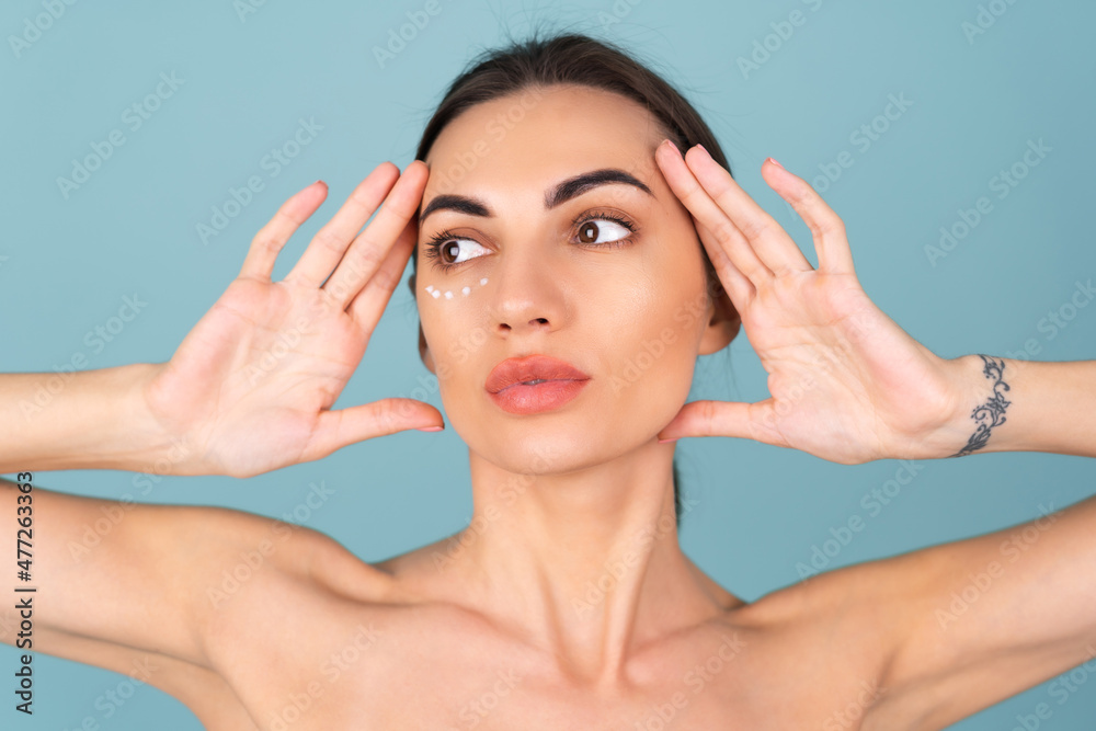 Naklejka premium Close-up beauty portrait of a topless woman with perfect skin and natural make-up, with anti-aging cream dots to moisturize and firm the skin under the eyes