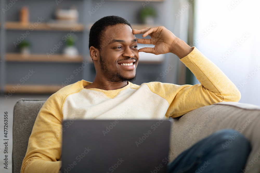 Dreamy black guy freelancer working online from home Dreamy black guy freelancer working online from home