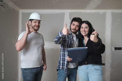 Young couple and architect celebrate the signing of the contract to buy a house.