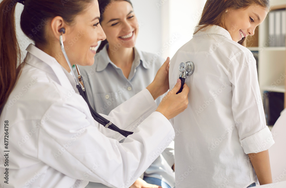 Friendly doctor examining child. Female pediatrician doing lungs exam for young patient. Happy preteen girl gets her respiration checked during routine checkup at clinic or hospital, close up Friendly doctor examining child. Female pediatrician doing lungs exam for young patient. Happy preteen girl gets her respiration checked during routine checkup at clinic or hospital, close up