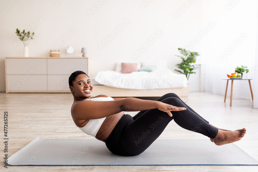 Overweight millennial black lady doing abs exercises training