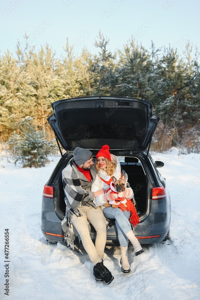Happy couple sitting in open car back, having stop off. Romantic traveling concept. Winter forest.