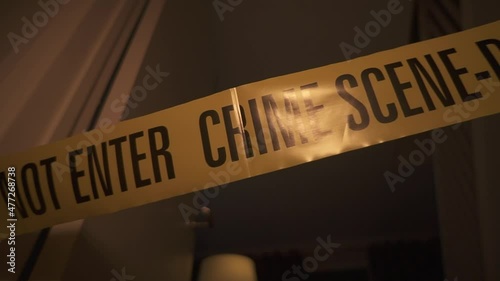 Crime Scene Do Not Enter around a door frame. Police men at a crime scene