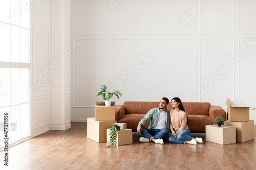 Arab family relaxing on floor in new home with boxes