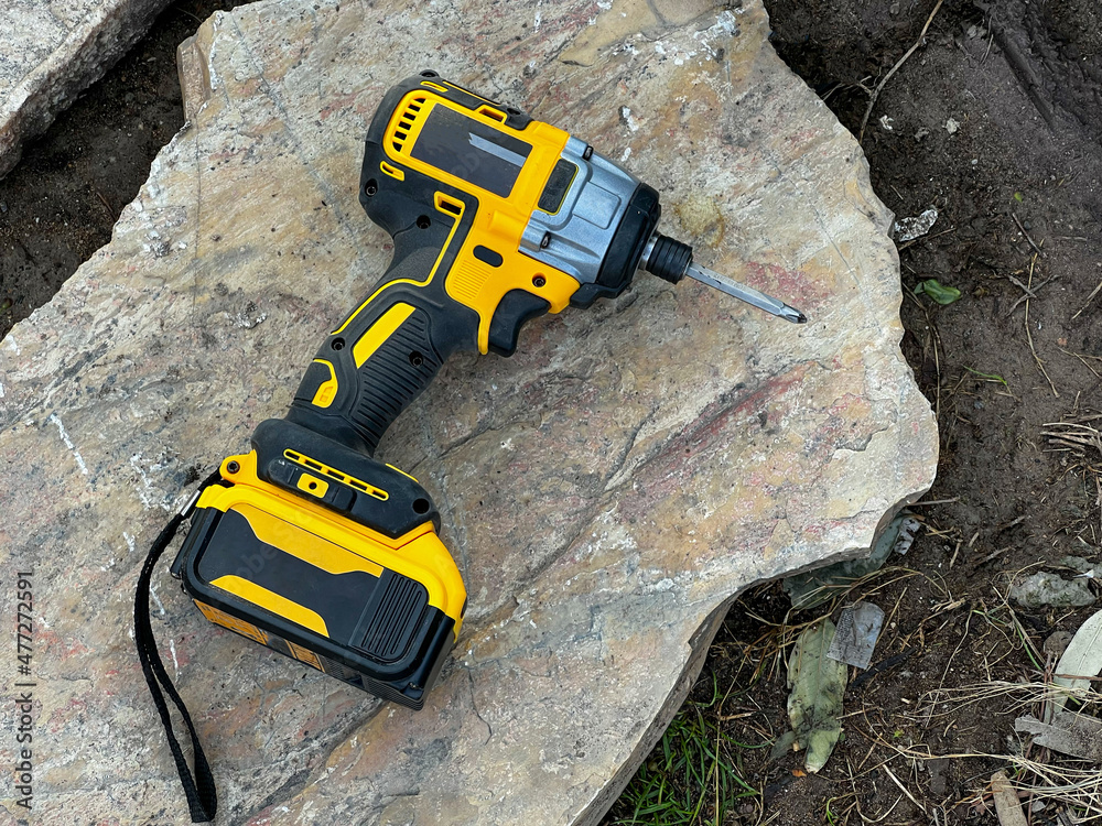 cordless screwdriver standing on rock on ground at construction site