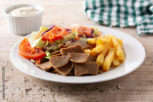 Plate of kebab  vegetables and french fries on wooden table