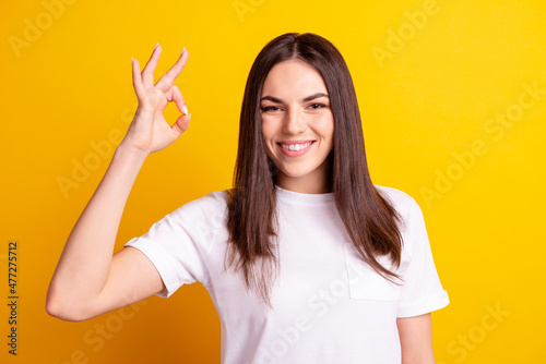 Photo of young girl show fingers okey symbol ads quality recommendation promotion isolated over yellow color background