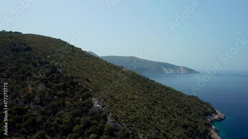Aerial flying through green hill reveal Scenic Kefalonia coastline, Fteri and Amidi beach photo