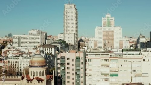 Fly above town buildings around colourful dome of Church of Saint Theresa and Saint Joseph. Revealing Spain square with tall buildings around.