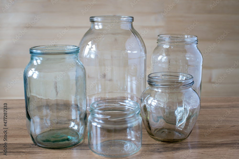 Glass jars of different sizes and volumes on the wooden table.