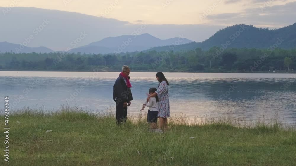 Happy family enjoying nature together on a summer day by the lake at sunset. Family spend together on vacation. Happy family enjoying nature together on a summer day by the lake at sunset. Family spend together on vacation.
