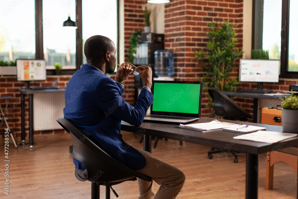 Business man looking at horizontal green screen on laptop to work on project planning. Employee working with chroma key and isolated mockup template on computer display in startup office. Business man looking at horizontal green screen on laptop to work on project planning. Employee working with chroma key and isolated mockup template on computer display in startup office.