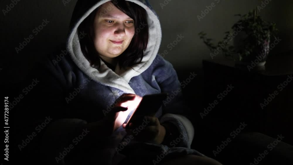 Close up of lonely young woman lying on sofa and using smartphone at night. Close up of lonely young woman lying on sofa and using smartphone at night.
