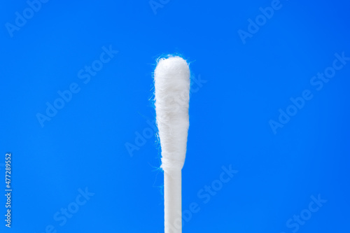 White cotton swab or or cotton bud against blue background. Coronavirus PCR or antigen rapid test for nasopharyngeal swab and detection of SARS-CoV-2. photo