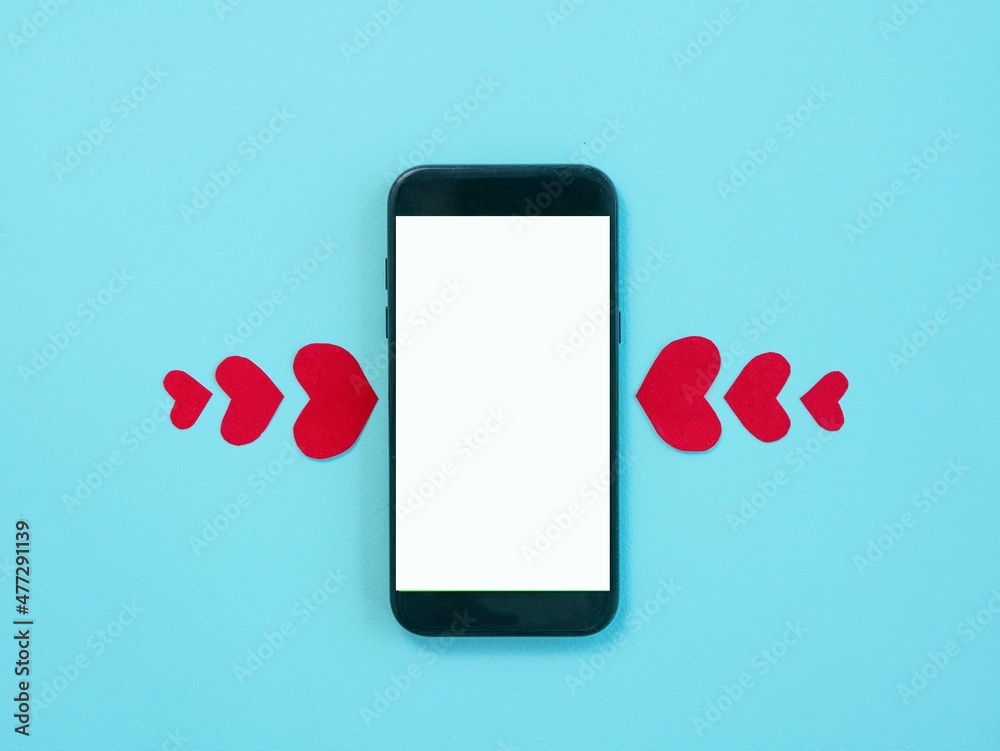 A smartphone with a white screen, red hearts from large to small on both sides of the phone. Love relationships by correspondence. Online dating concept. Valentine's Day.