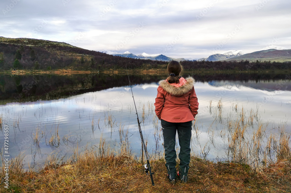 woman in mountain scenery with fishing rod scout over beautiful landscape during fall. woman in mountain scenery with fishing rod scout over beautiful landscape during fall.