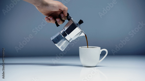 cropped view of man pouring coffee into cup on white and grey. photo