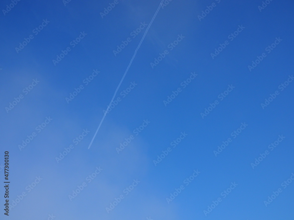 Trace of the airplane flying across a blue sky. White clouds in a blue sky. Vapour trail. Trace of the airplane flying across a blue sky. White clouds in a blue sky. Vapour trail.