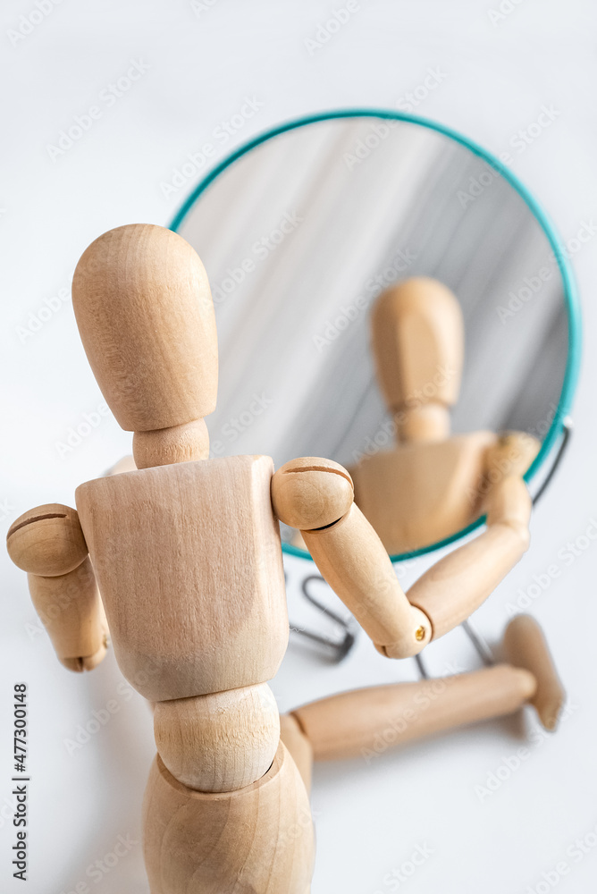 Wooden dummy looks at its reflection in the mirror Wooden dummy looks at its reflection in the mirror