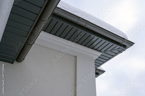 Fotografia Corner of the house with new gray metal tile roof and rain gutter covered by snow at winter