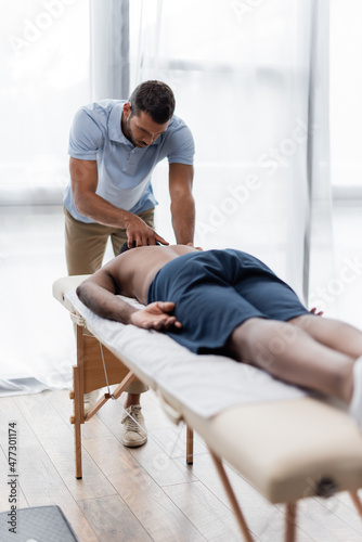 young physiotherapist doing neck massage to african american man on blurred foreground © LIGHTFIELD STUDIOS