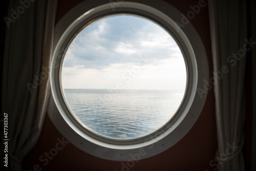 Fotografia Blick aus einem runden Schiffsfenster auf das Meer