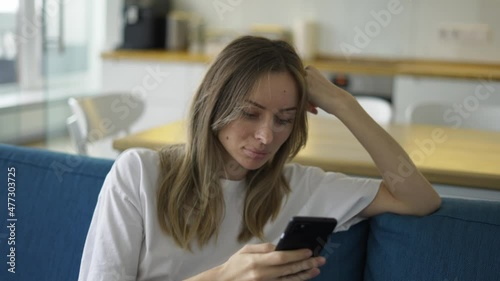 Calm woman surfing in Internet at phone in apartment on couch photo