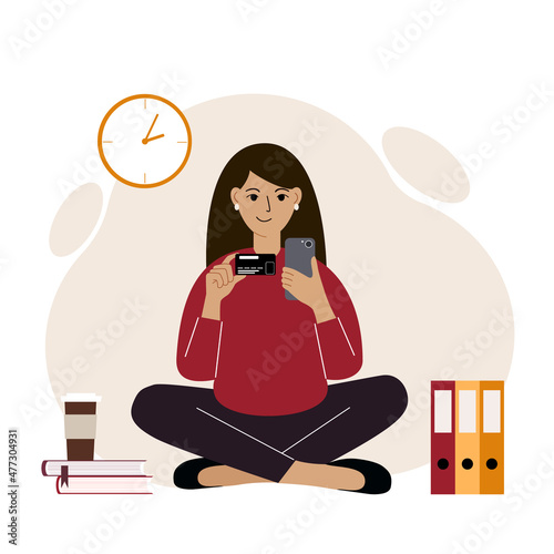 A woman sits cross-legged with a mobile phone in one hand and a bank card in the other. Concept of online credit