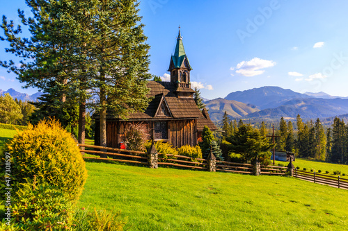 Beautiful wooden church Plazowka built in traditional style architecture on green meadow with view of Tatra Mountains, Koscielisko, Poland