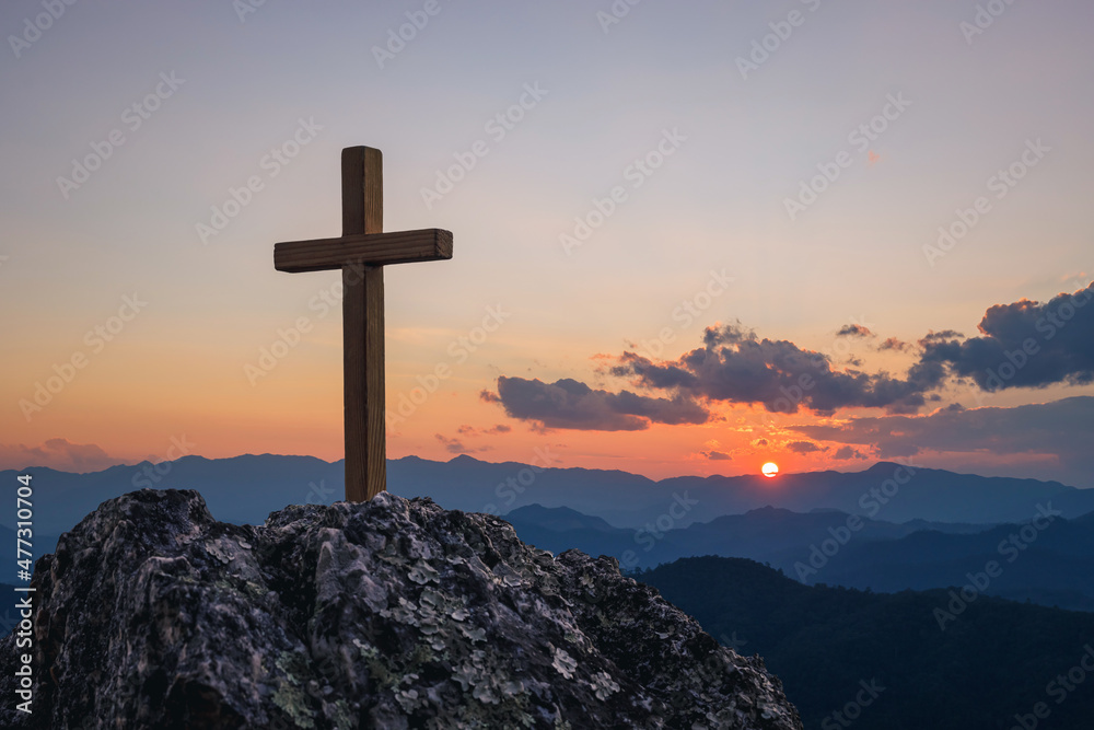 Silhouettes of crucifix symbol on top mountain with bright sunbeam on the colorful sky background Silhouettes of crucifix symbol on top mountain with bright sunbeam on the colorful sky background