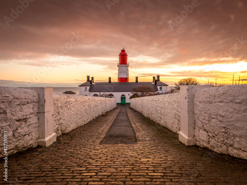 The pathway to the red and white striped, 23 meter tall, Souter Lighthouse in Marsden, South Shields as the sun rises