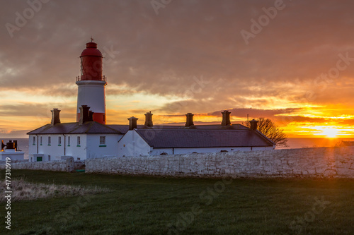 The red and white striped  23 meter tall   Souter Lighthouse and the Leas in Marsden  South Shields  England  as the sun rises