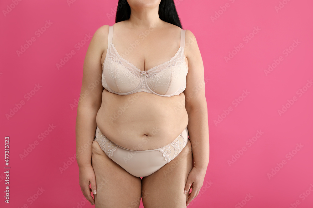 Obraz premium Overweight woman in beige underwear on pink background, closeup. Plus-size model